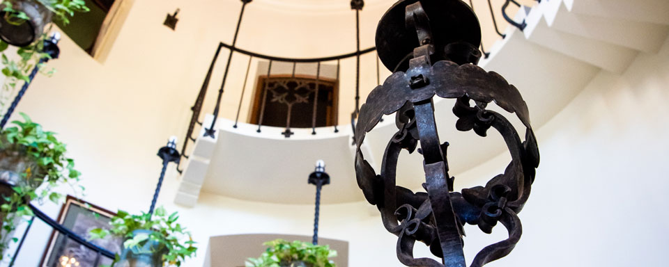 A photo of the spiral staircase inside Ewing manor; a metal candlestick attached to the stair railing sits in frame.