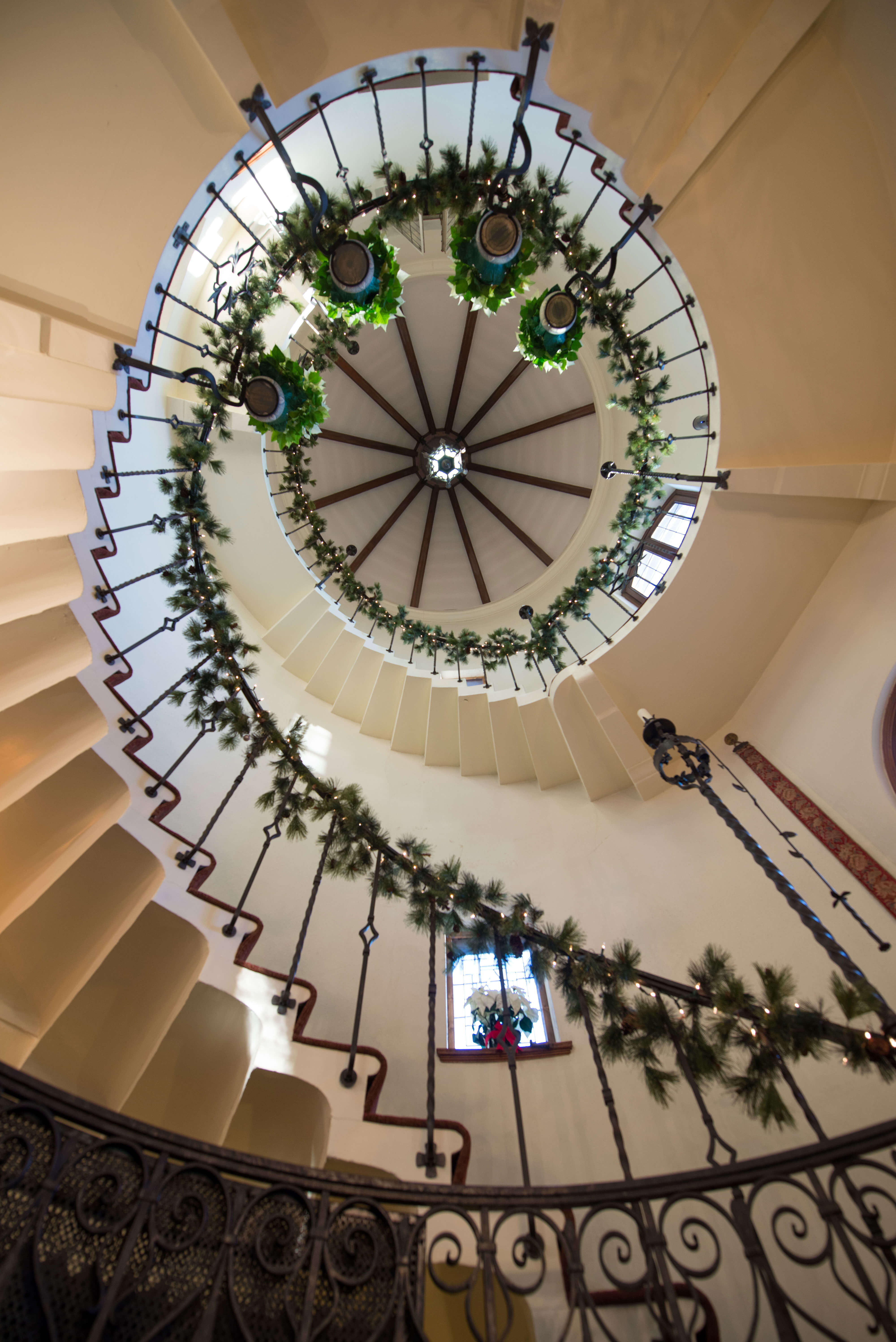The view under the spiral staircase decorated with poinsettas, lights, and garland.