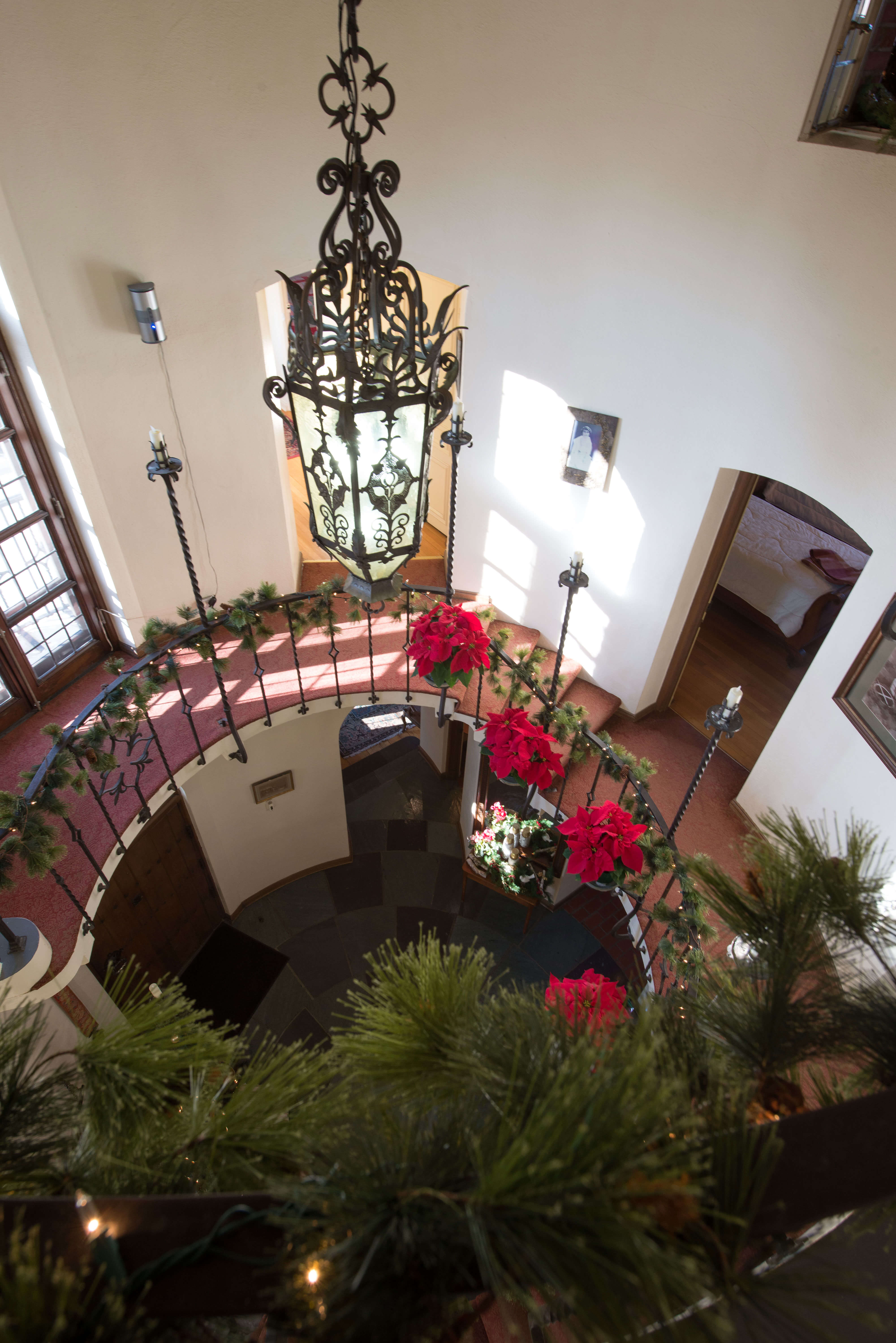The view from the up of the spiral staircase decorated with poinsettas, lights, and garland.