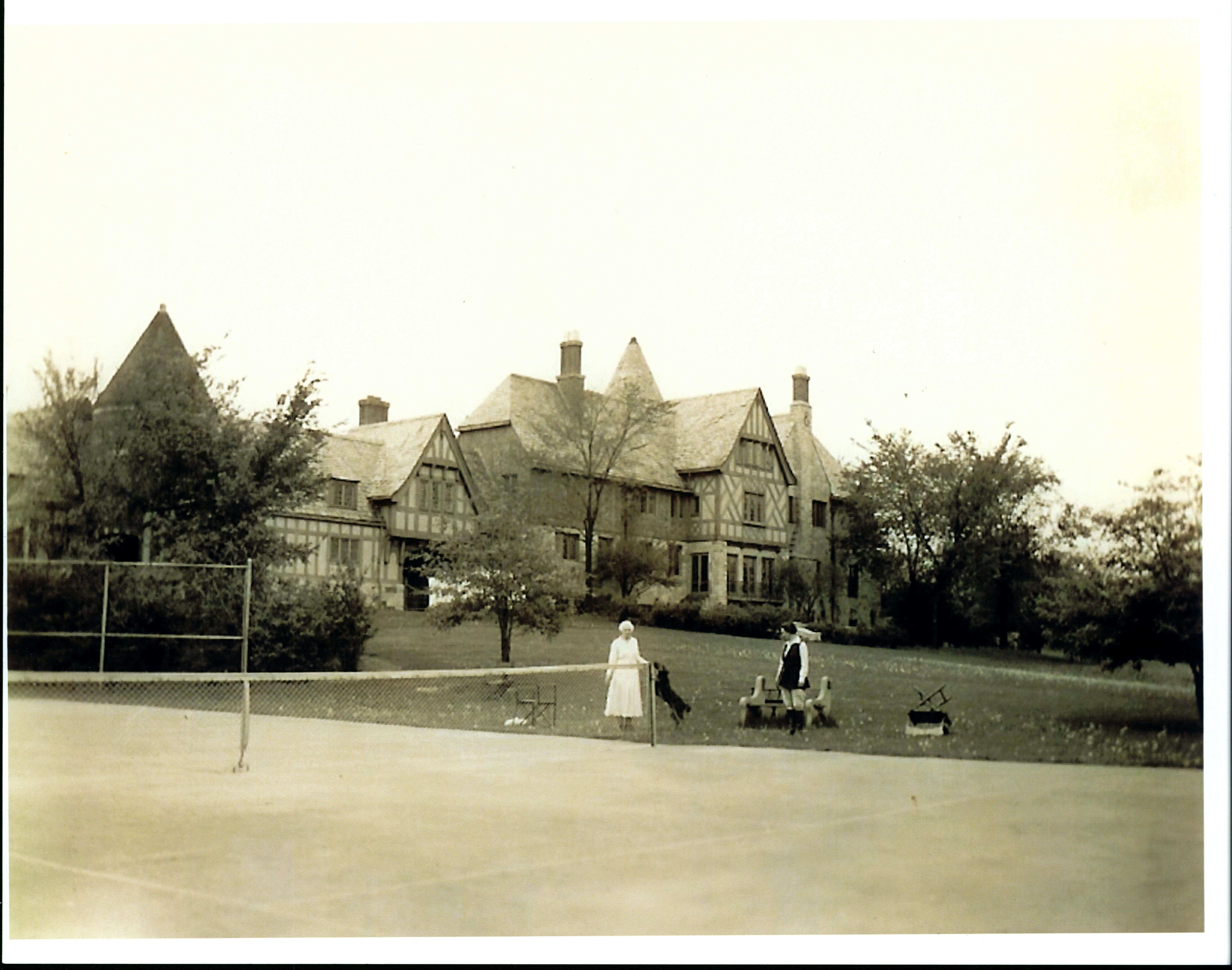 Women and dogs in front of the tennis court.