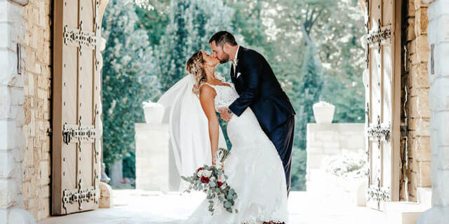 Bride and groom kiss in front of the gate.